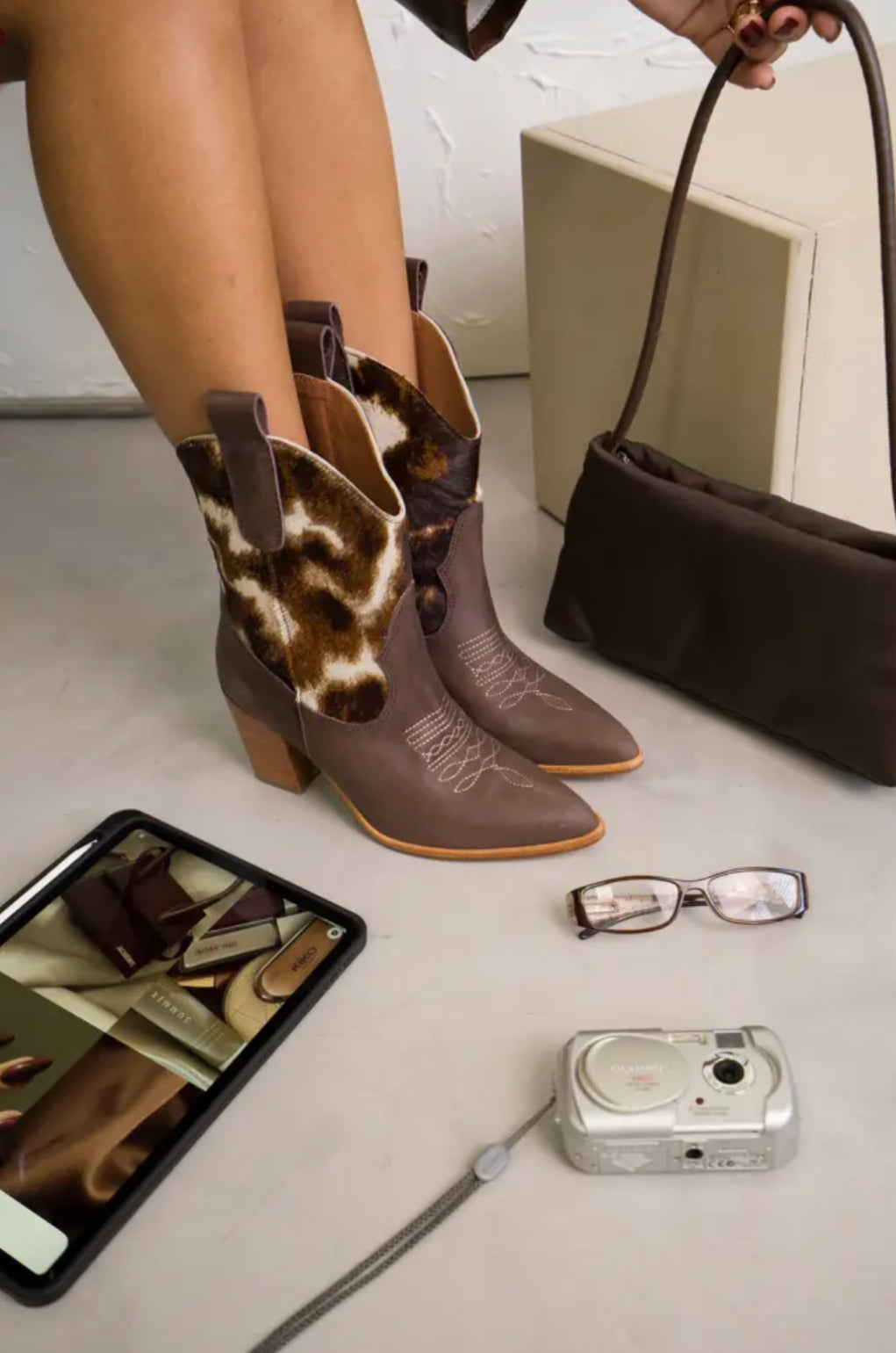 Rich tan leather ankle boots featuring warm orange-and-white cow-print uppers, wooden stacked heels, and engraved detailing. A bold Western statement for stylish day-to-night wear.