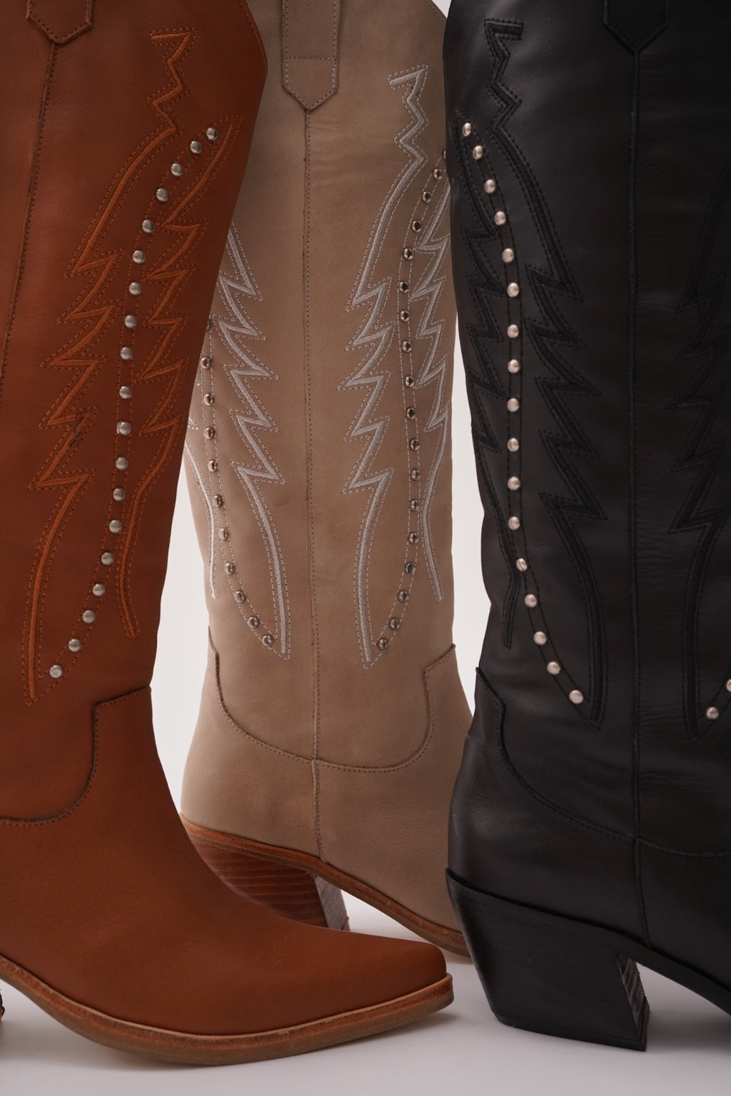 Classic tall cowboy boots with pointed toes, angled block heels, and intricate tonal embroidery on the shaft. A timeless Western silhouette with a sleek, all-black finish for versatile, edgy styling.