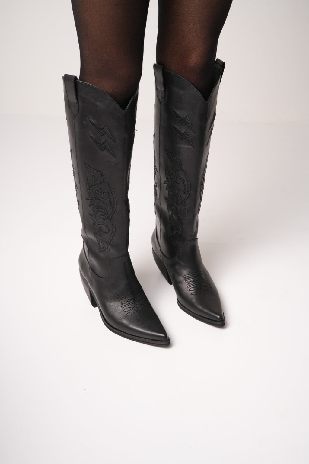 Classic tall black cowboy boots with pointed toes, angled block heels, and intricate tonal embroidery on the shaft. A timeless Western silhouette with a sleek, all-black finish for versatile, edgy styling.
