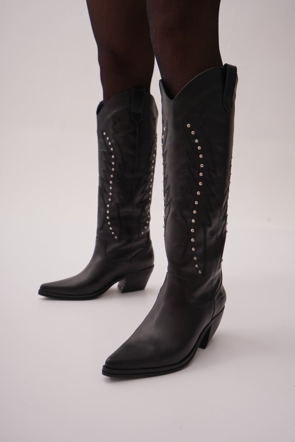 Classic tall black cowboy boots with pointed toes, angled block heels, and intricate tonal embroidery on the shaft. A timeless Western silhouette with a sleek, all-black finish for versatile, edgy styling.
