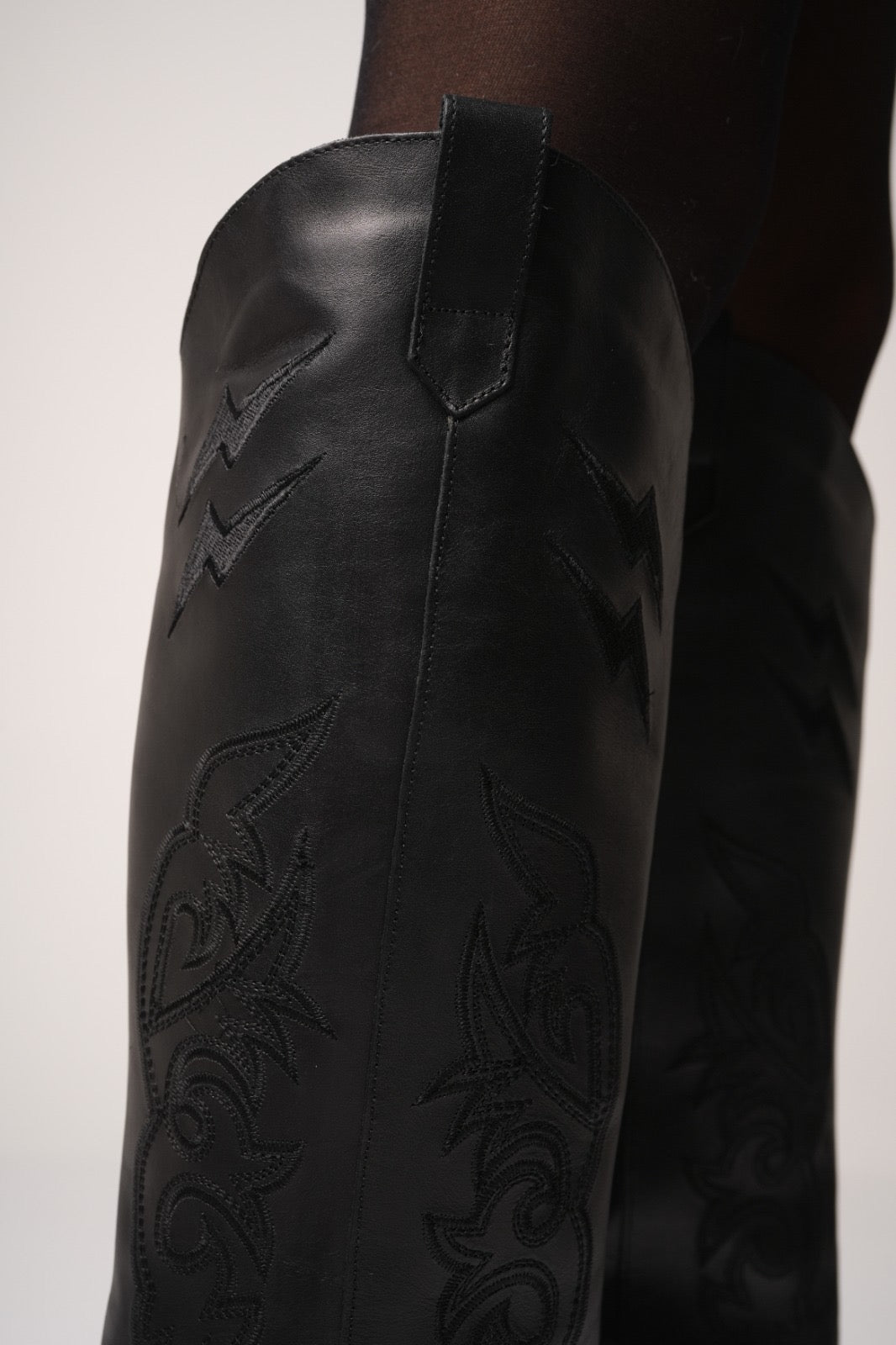 Classic tall black cowboy boots with pointed toes, angled block heels, and intricate tonal embroidery on the shaft. A timeless Western silhouette with a sleek, all-black finish for versatile, edgy styling.