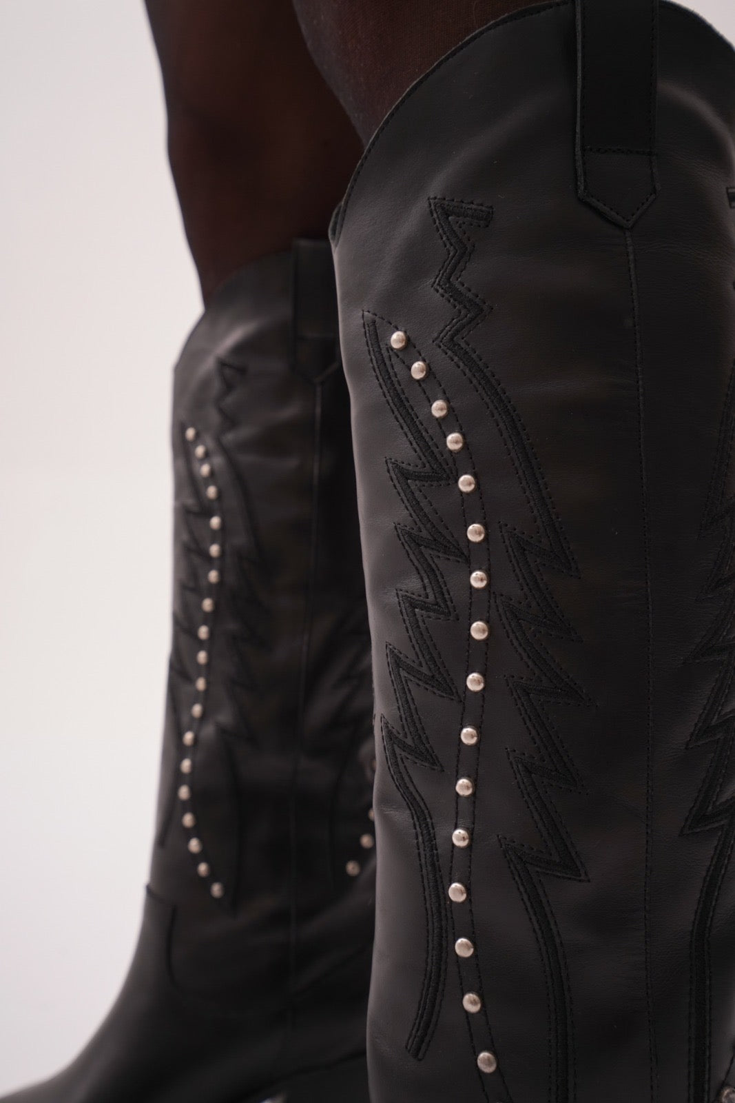 Classic tall black cowboy boots with pointed toes, angled block heels, and intricate tonal embroidery on the shaft. A timeless Western silhouette with a sleek, all-black finish for versatile, edgy styling.