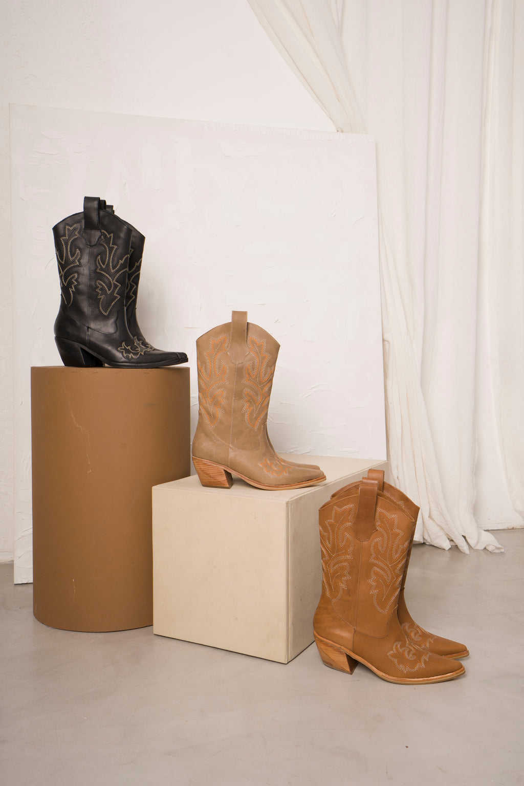 Classic mid-calf cowboy boots in rich tan leather, featuring intricate white Western stitching, pointed toes, and angled wooden block heels. A timeless rustic design perfect for everyday wear or elevated country-chic outfits.