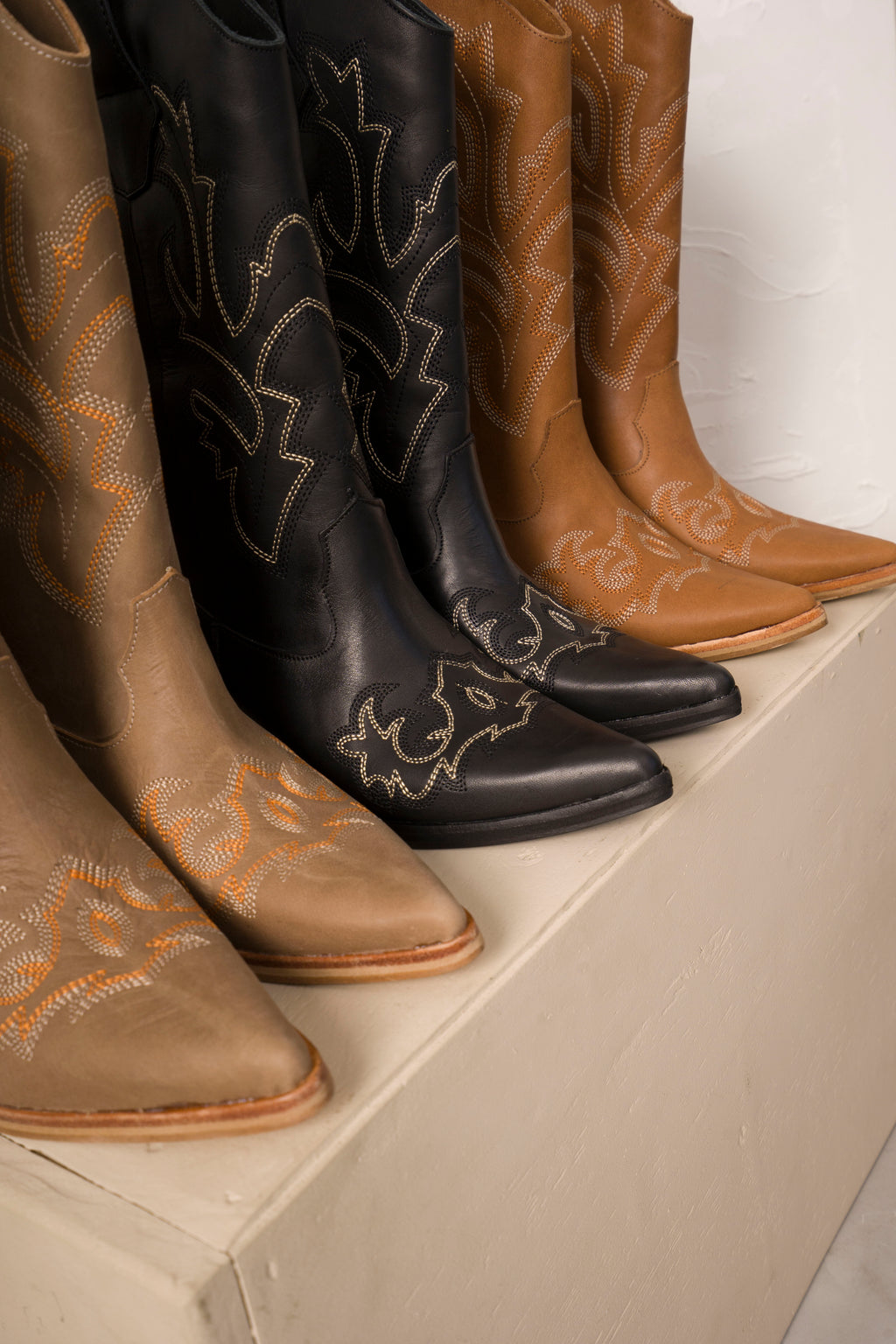 Classic mid-calf cowboy boots in rich tan leather, featuring intricate white Western stitching, pointed toes, and angled wooden block heels. A timeless rustic design perfect for everyday wear or elevated country-chic outfits.