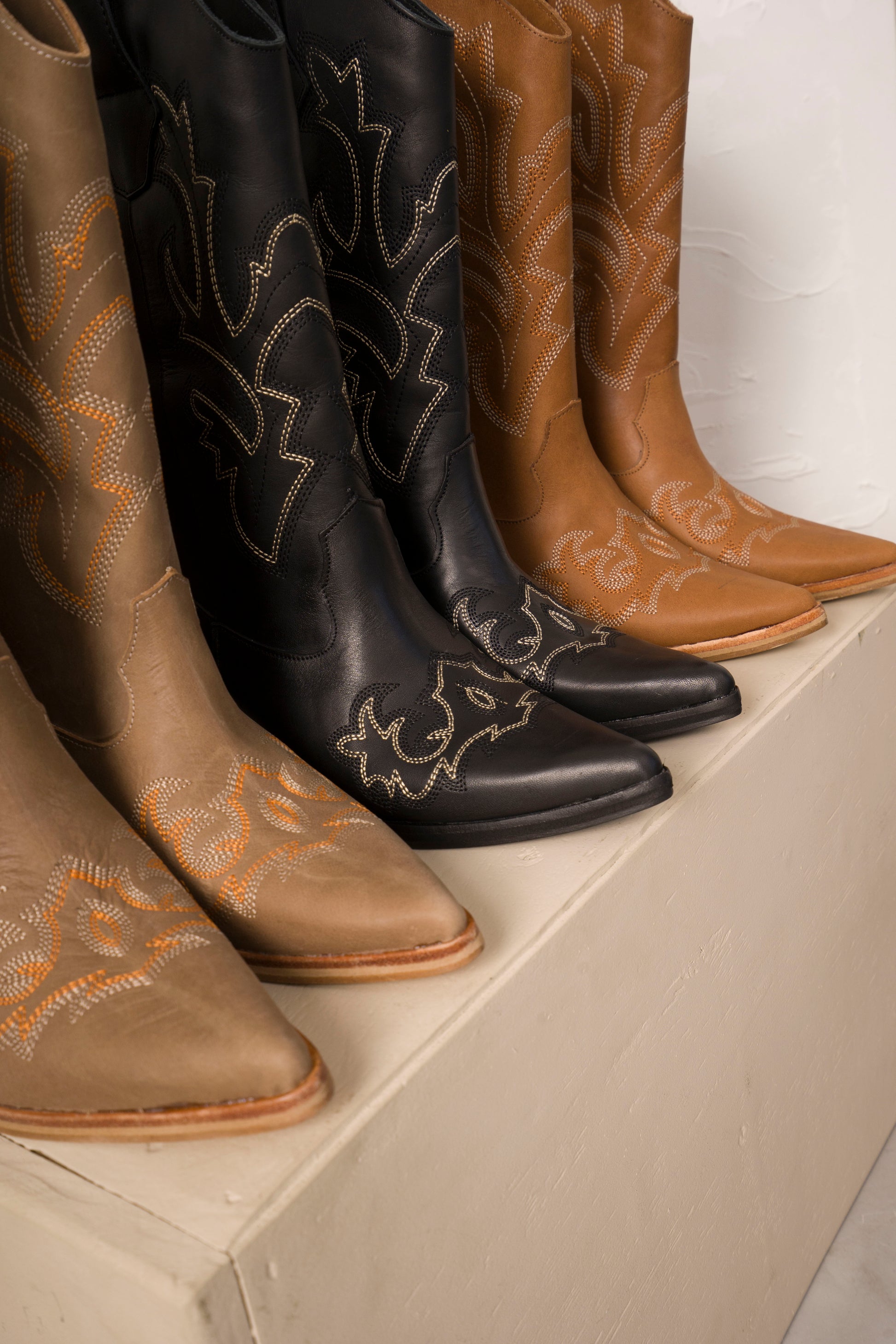 Classic mid-calf cowboy boots in rich tan leather, featuring intricate white Western stitching, pointed toes, and angled wooden block heels. A timeless rustic design perfect for everyday wear or elevated country-chic outfits.