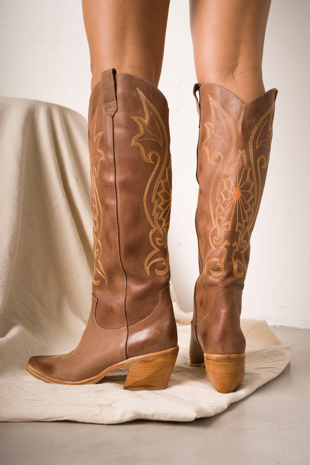 Tall black cowboy boots with pointed toes, angled heels, and subtle black-on-black Western embroidery along the shaft. A sleek and edgy twist on a classic silhouette, perfect for bold, versatile styling.