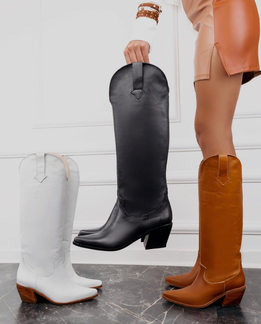 Sleek knee-high black leather boots with a subtle Western silhouette, square toes, and mid-height block heels. A modern, minimalist design ideal for versatile day-to-night styling.